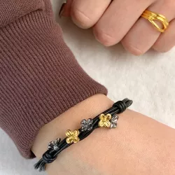 svart armbånd i lær med blomsteranheng i forgylt og rhodinert sølv